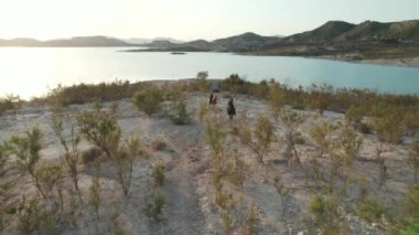 Hava aracı bakış açısına göre iki yetişkin beyaz kadın açık havada atlara biniyor. La Pedrera Gölü manzaralı mumyalama, Orihuela. İspanya. Hobi, binicilik sporu ve aktif yaşam tarzı kavramı