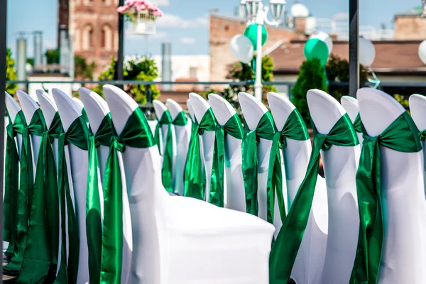 白色的婚纱椅子用绿丝带系在户外 — 图库照片