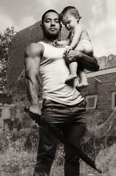 Father hugging a baby and holding a sword — Stock Photo, Image