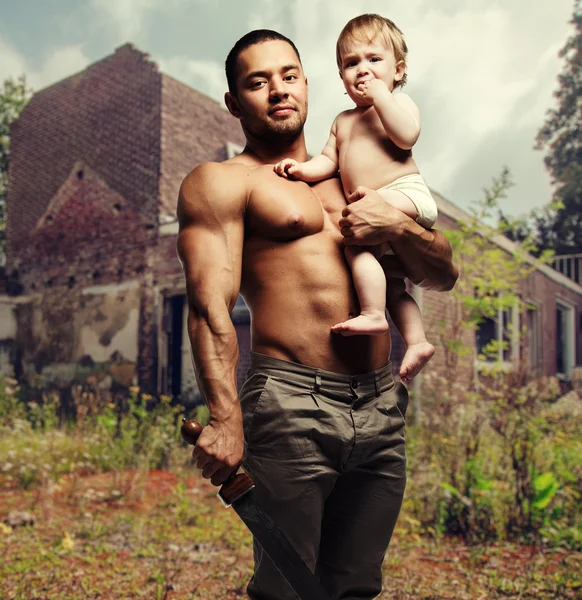 Father hugging a baby and holding a sword — Stock Photo, Image