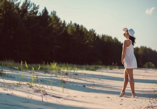 Vrouw dragen witte korte jurk en een witte hoed die zich voordeed op het strand — Stockfoto