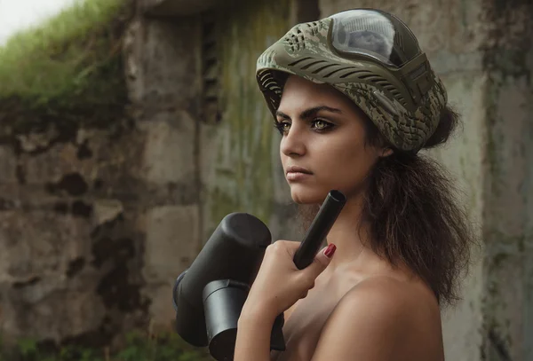 Young naked brunette holding paintball gun — Stock Photo, Image