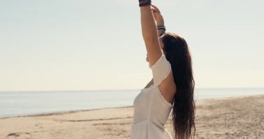 Beyaz elbiseli genç bir kadın kollarını gökyüzüne kaldırmış güneşli sahilde duruyor. Okyanusun özgürlüğünü ve huzurunu hissediyor. Doğa ve iç denge kavramı ile derin bağlantı