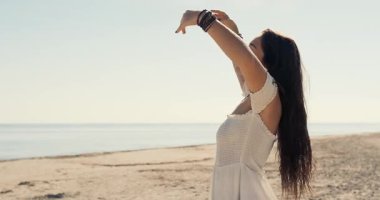 Beyaz elbiseli genç bir kadın kollarını gökyüzüne kaldırmış güneşli sahilde duruyor. Okyanusun özgürlüğünü ve huzurunu hissediyor. Doğa ve iç denge kavramı ile derin bağlantı