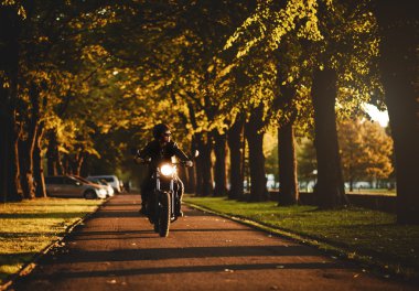 Man riding a cafe-racer motorcycle outdoors clipart