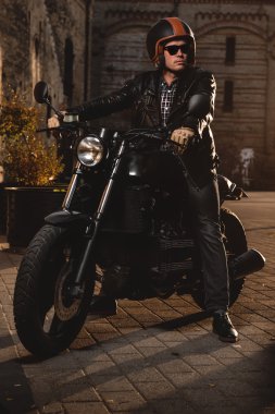 Açık havada bir kafe-racer motosiklet üzerinde oturan adam