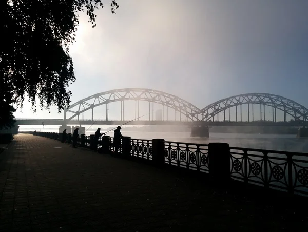 Pêcheur sur le remblai de Daugava et le pont ferroviaire — Photo