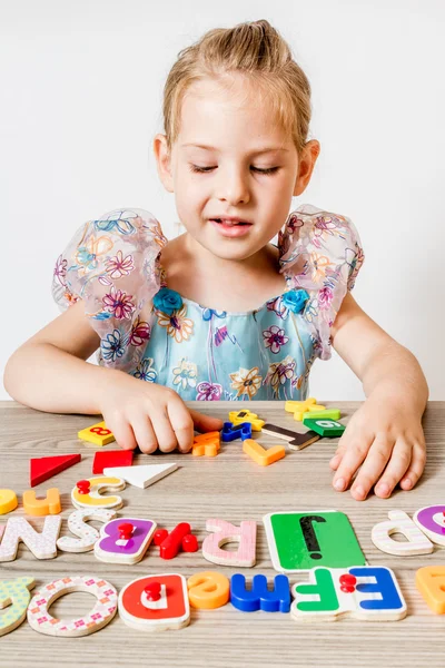 Ξανθό κοριτσάκι παίζει με τα πολύχρωμα γράμματα Royalty Free Εικόνες Αρχείου