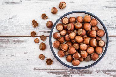 Beyaz ahşap masa üzerinde emaye kase fındık