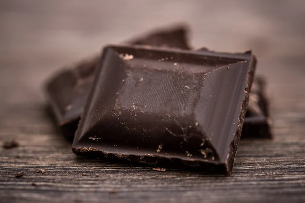 Chopped barras de chocolate escuro na mesa de madeira — Fotografia de Stock