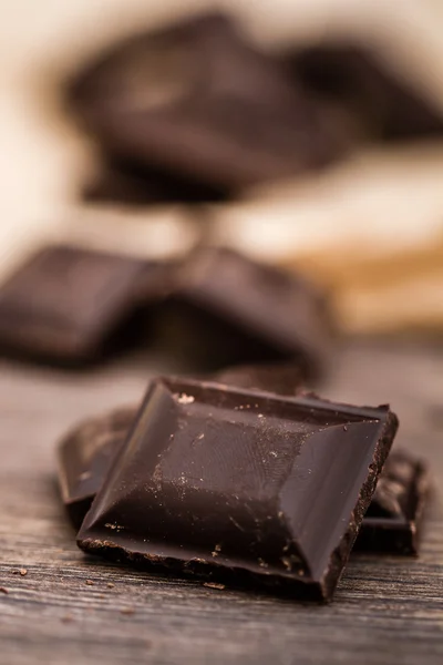 Barres de chocolat noir sur papier émietté et table en bois — Photo