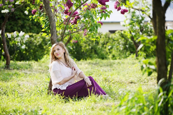 Kvinna sitter under en lila buske — Stockfoto