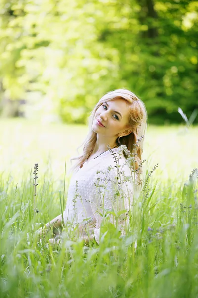 Mooi meisje zit in het gras — Stockfoto