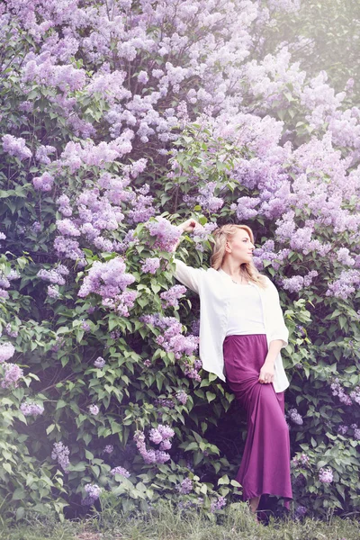 Mulher perto do lilás florescente, matizado — Fotografia de Stock