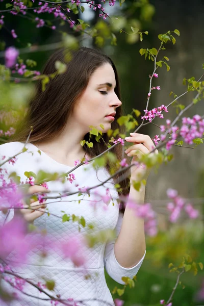 Žena, vonící květy na stromě — Stock fotografie