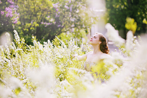Beautiful girl in a big spirea bush, girl enjoying nature