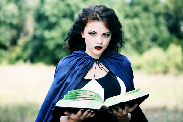 Beautiful young witch with with a book of spells