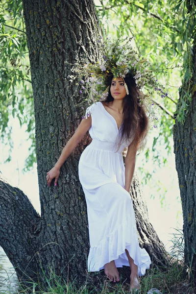 Girl in a wreath near the tree — Stock Photo, Image