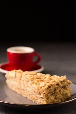 Napolyon keki yakın plan ve arka planda bir fincan kahve.