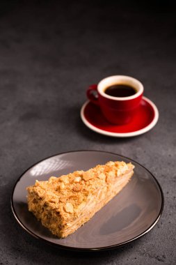 Napolyon keki yakın plan ve arka planda bir fincan kahve.