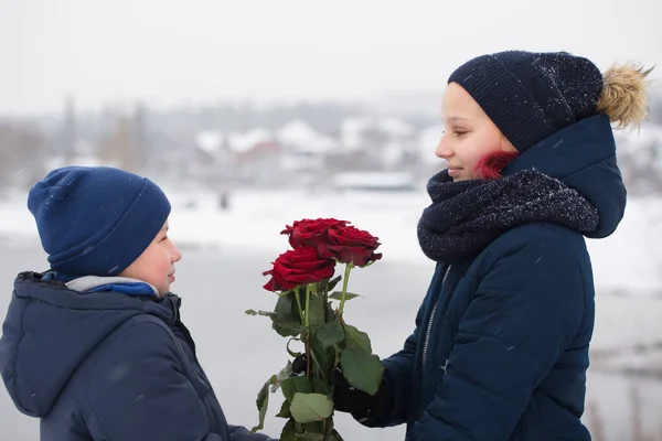 少年は少女に赤いバラを与えます — ストック写真