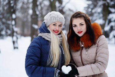 Sevgililer Günü 'nde kardan kalp taşıyan iki kız arkadaş.