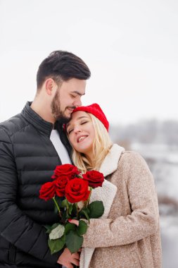 Genç yakışıklı bir adam sevgililer gününde bir buket gül veriyor.