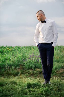 Yaz çimlerinde yürüyen damadın portresi.