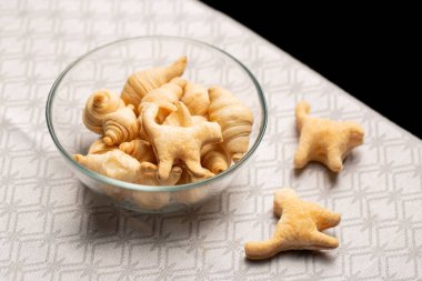 İçinde poğaça kruvasan ve kedi şeklinde kurabiyeler olan cam kase. Ev yapımı kuru kahvaltı gevreği, çocuklar için yaratıcı Cadılar Bayramı atıştırmalığı fikri ve neşeli sabahlar..