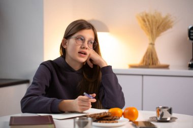 Genç kız ev ödevi hakkında yüksek sesle düşünür ve konuşur sıcak akşam ışığında, dikkatli öğrenme ve dengeli yaşam tarzını vurgular.