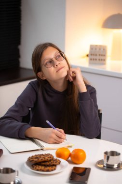 Genç kız rahat masada notlar yazarken rüya görüyor. Huzurlu bir duraksama ve sıcak akşam atmosferiyle düşünceli bir öğrenme.