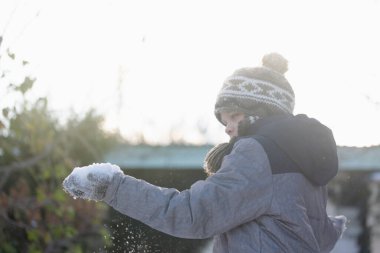 Dikkatli çocuk karlı bir günde dışarıda durur, elinde karı, farkındalığın, merakın ve doğayla olan sessiz bağın sembolünü gözlemler.