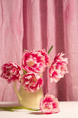 Seramik bir sürahide pembe laleli fotorealistik natüralistik natüralistik yaşam yumuşak kumaş arka planda, zarif doğal ışık ve sakin atmosfer, anneler günü, doğum günü, doğum günü, kutlama, tebrik kartı, ev dekorasyonu ve yaşam tarzı kullanımı için uygun.