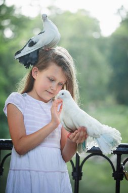 Genç kız beyaz güvercine nazikçe dokunurken başka bir güvercin kafasının üstünde duruyor. Barış, güven, şefkat, çocukluk masumiyeti, doğayla uyum..