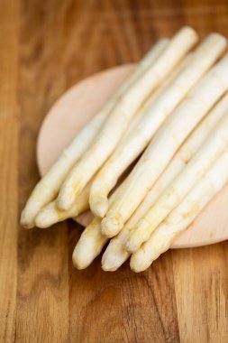 Yuvarlak tahta üzerinde taze beyaz kuşkonmaz, üst manzara, doğal ışık, mevsimsel sağlıklı sebzeler..