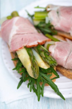 Beyaz tabakta kuşkonmaz, prosciutto ve roka, taze gurme atıştırmalık konsepti..