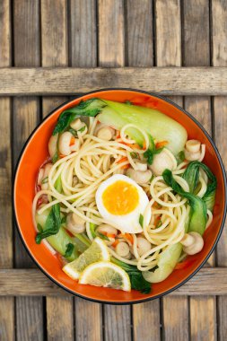 Çin lahanalı Asya eriştesi çorbası, kaynamış yumurta ve mantarlar parlak kasede. Taze sağlıklı yemek konsepti.