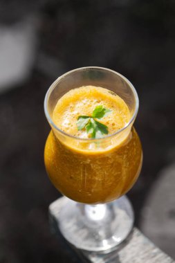 Bahçedeki bankta maydanayla süslenmiş sağlıklı bir bardak smoothie.