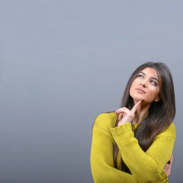 Mujer hermosa mirando el área en blanco contra el fondo gris — Foto de Stock