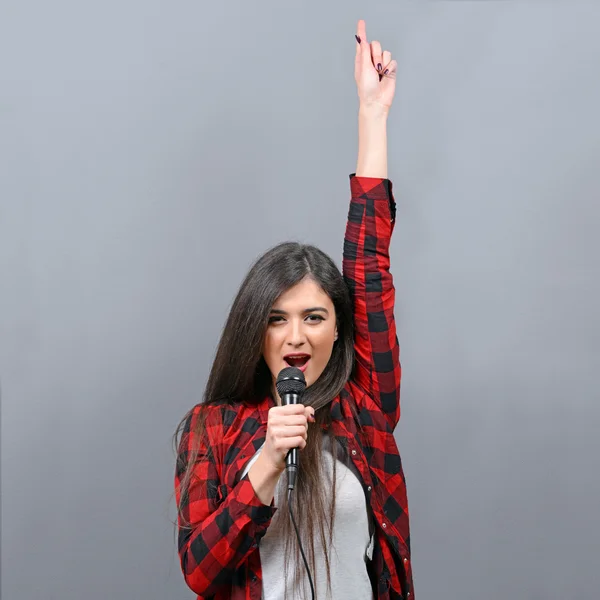 Bella donna che canta con il microfono contro il backgro grigio — Foto Stock