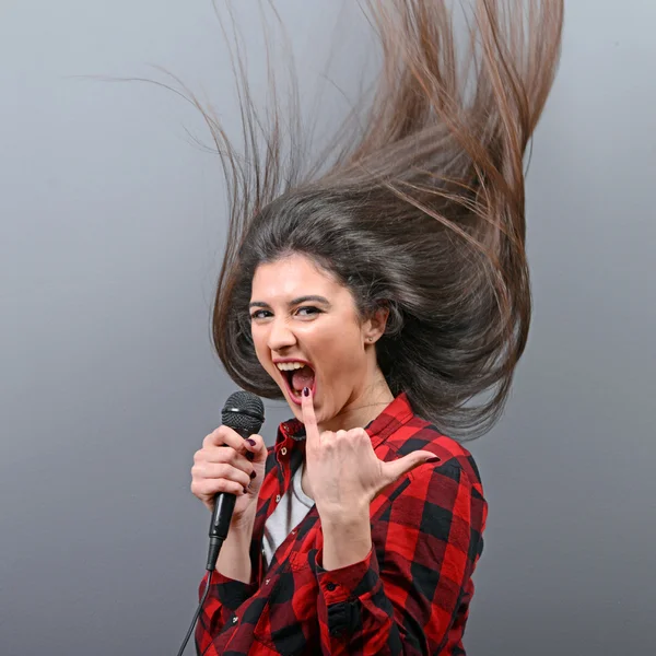Szép nő, éneklés a mikrofon szürke backgro ellen — Stock Fotó
