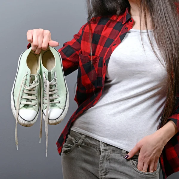 Mujer feliz sosteniendo zapatillas retro sobre fondo gris — Foto de Stock