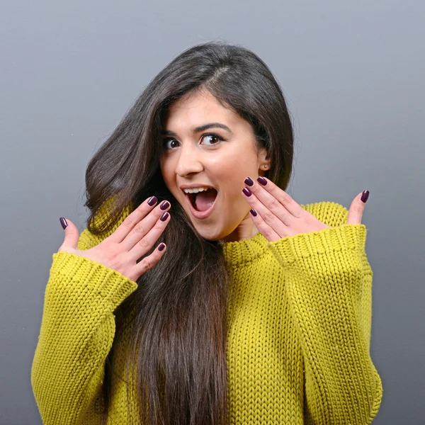 Portrait of a ecstatic woman with spread hands against gray back — Stock Photo, Image