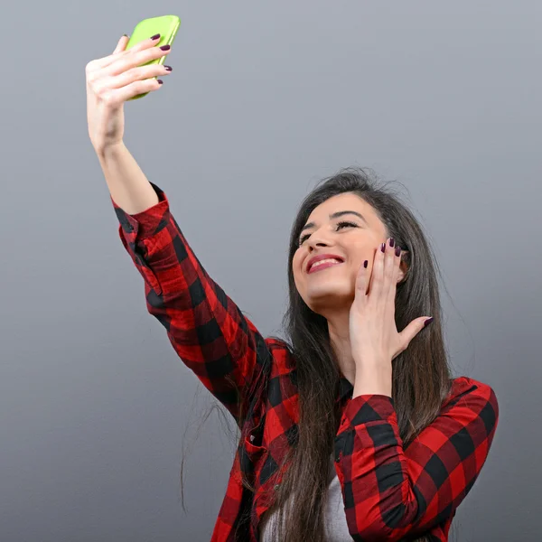 Portrait of a girl taking selfie with cellphone against gray bac — Stock Photo, Image