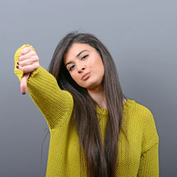 Retrato de una mujer mostrando el pulgar hacia abajo como desaprobación contra gr — Foto de Stock