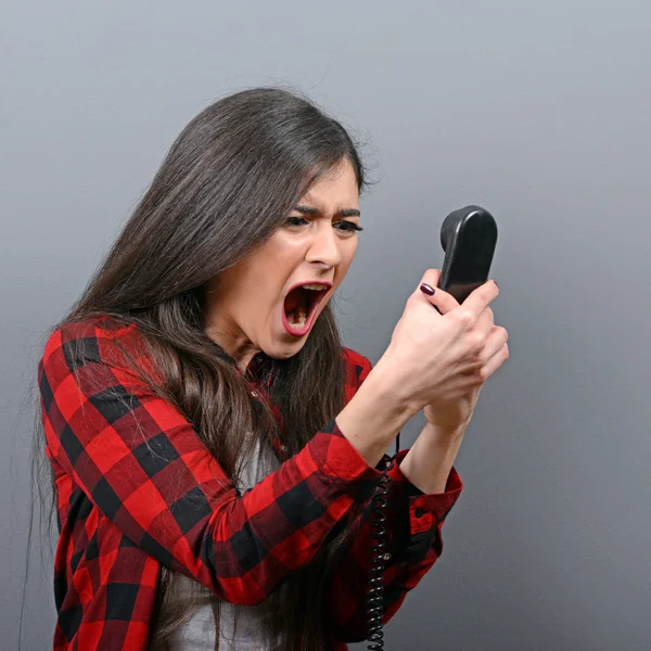 Retrato de una mujer gritándole al teléfono contra un fondo gris —  Fotos de Stock