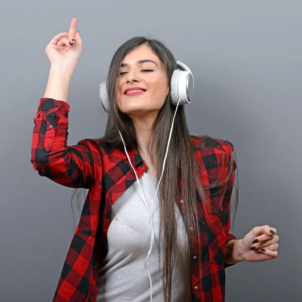 Portret van dansende stedelijke vrouw met hoofdtelefoon tegen grijze bac — Stockfoto