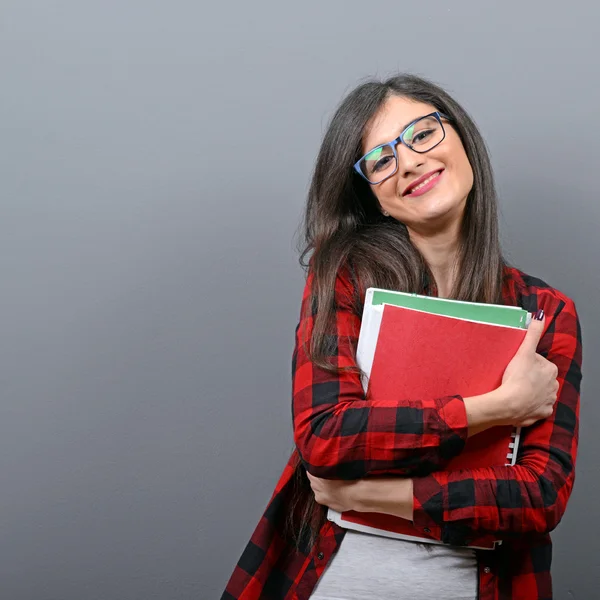 Portrait of happy student woman holding books against gray backg — Stock Photo, Image