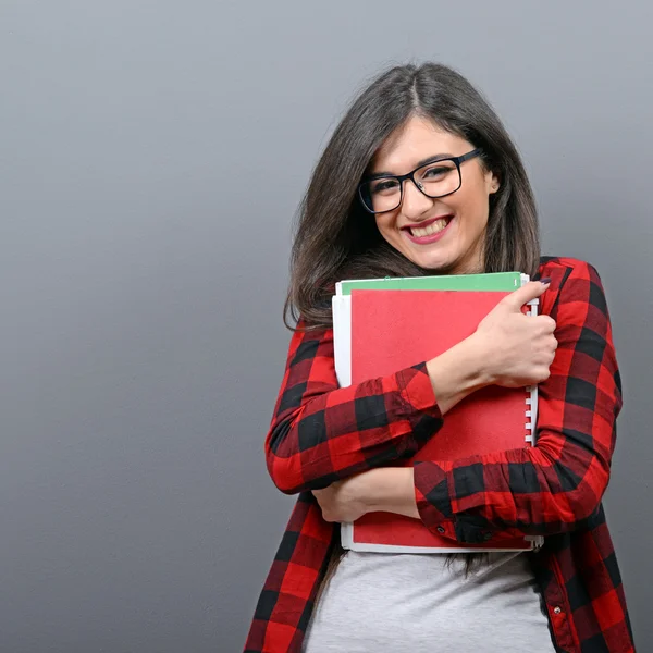 Portrait of happy student woman holding books against gray backg — Stock Photo, Image