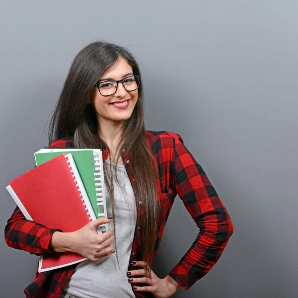 Portrait of happy student woman holding books against gray backg — Stock Photo, Image